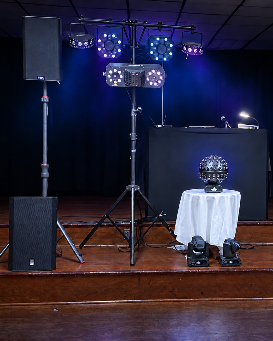 D&J Entertainment speakers, light bar, DJ booth, and mirror ball set up on stage